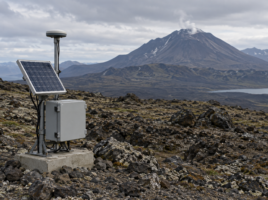 Station de surveillance équipée d’une antenne et d’un panneau solaire sur un terrain volcanique.
